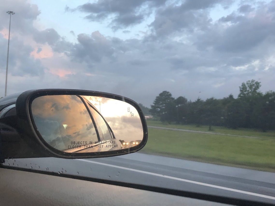 sunrise in the rearview mirror of a car